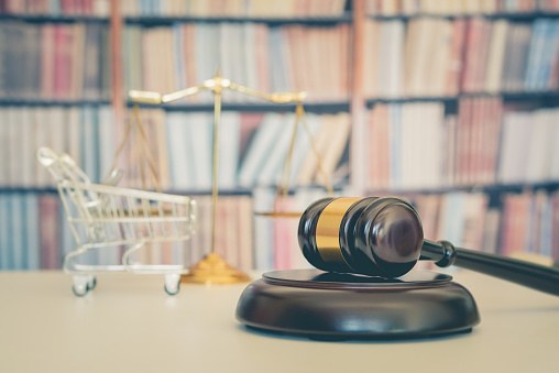 Gavel and shopping cart in front of books